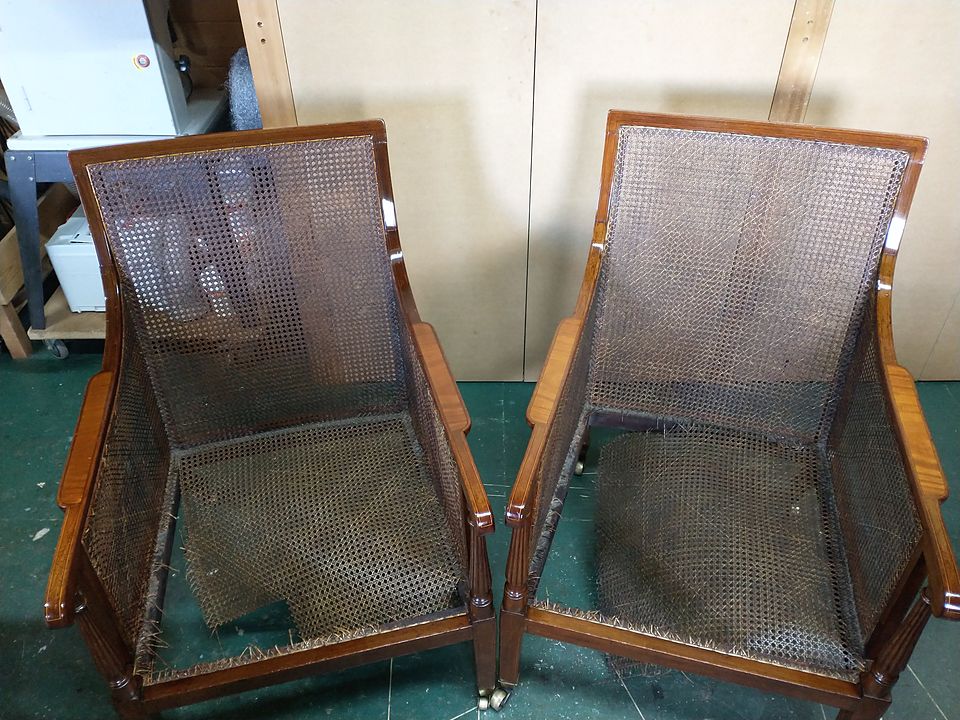 Pair of bergere armchairs with torn cane backs, sides and seats, before recaning