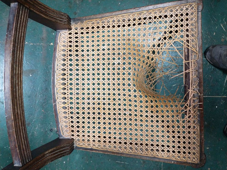 A hand-caned seat with a broken, sagging hole in the middle