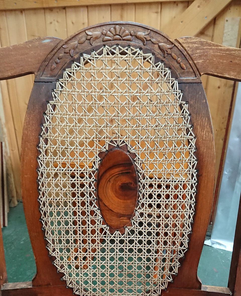 Oval chair back with hand-woven cane and a carved crest rail, around a figured centre panel